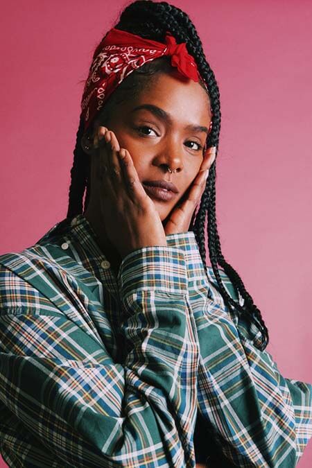Black womxn with a professional box braids wearing a red bandana as a headband hairstyle with her palms on her cheeks