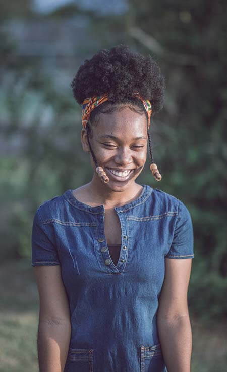 Black womxn with a professional fulani braids and beads hairstyle covered wearing a colorful headband and smiling