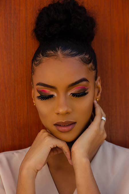 A portrait shoot of a black womxn with a professional hairstyle of a hair put in a bun and styled baby hairs