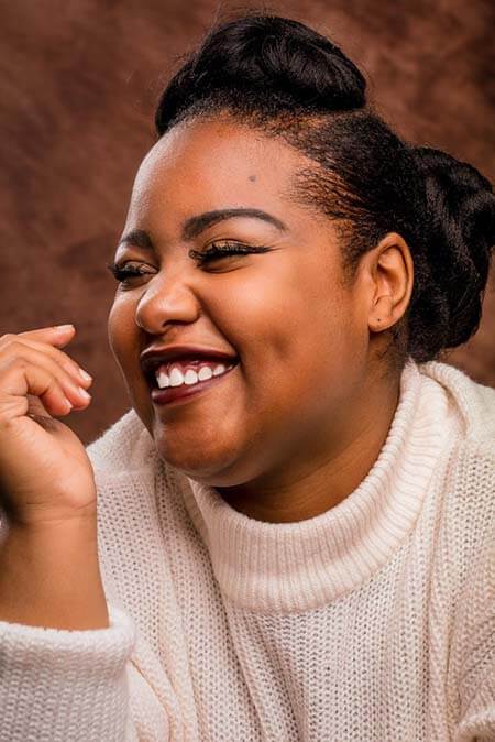 Black womxn with a professional hairstyle divided into 2 parts - one in a top structured bun, another in a mid bun